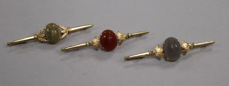A pair of yellow metal bar brooches and another similar, each set with an oval hardstone cabochon in