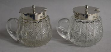 A pair of Edwardian silver mounted cut glass single handled preserve jars, with hinged covers, A.C.M