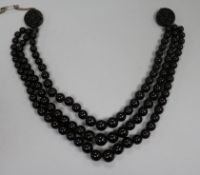 A triple strand simulated dark amber graduated bead choker necklace with carved disc terminals.