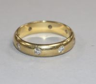 An 18ct gold and seven stone gypsy set diamond band, size L.