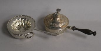 A late 19th century Hanau white metal pan and cover with turned handle, a sliver tea strainer and