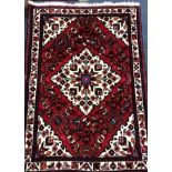 A Persian red and cream lozenge pattern rug 150 x 108cm.