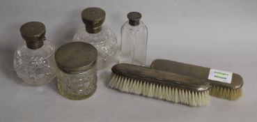 A pair of clothes brushes, cologne bottles and a hair tidy & bottle