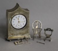 Three miniature silver chairs and a silver mantel timepiece.