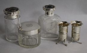 Two George V silver and tortoiseshell topped jars, a silver topped jar and a pair of small vases.