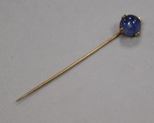 A yellow metal and cabochon star sapphire stick pin, 69mm.