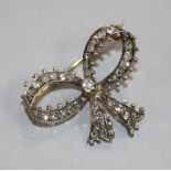 An Edwardian yellow metal and diamond set ribbon bow brooch, 33mm.