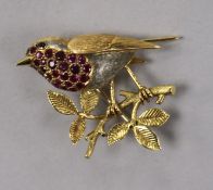 A yellow metal and gem set bird brooch, modelled as a robin on a branch, 35mm.