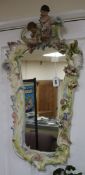 A shaped rectangular pottery wall mirror, encrusted with flowers and with cherub surmount, H 87cm