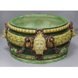 A large majolica circular jardiniere, glazed in green, brown and yellow and applied with mask and