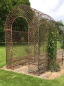 A steel rose bower of arched form with two slatted seats, L 200cm x H 297cm