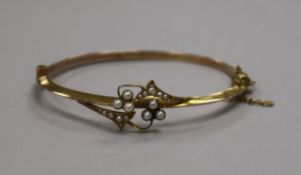 A cased Edwardian 9ct gold and seed pearl set hinged bangle.