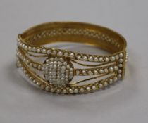 A Middle Eastern? yellow metal and multi seed pearl set hinged bangle.