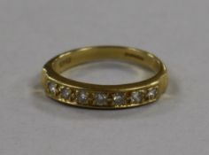 An 18ct gold and seven stone diamond half eternity ring, size R.