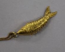 A yellow metal articulated fish pendant, on a fine link chain, pendant 36mm.