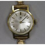 A lady's yellow metal Tissot manual wind wrist watch on a 9ct gold bracelet.