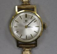 A lady's yellow metal Tissot manual wind wrist watch on a 9ct gold bracelet.