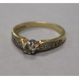 An 18ct gold and single stone diamond ring, with diamond set shoulders, size R.