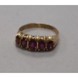 A late Victorian 9ct gold and graduated five stone garnet half hoop ring, size N.