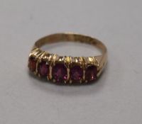 A late Victorian 9ct gold and graduated five stone garnet half hoop ring, size N.