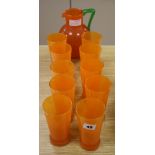 An orange and green glass jug and ten glasses