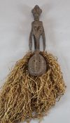 A tribal carved wood figure with sago palm leaf fringe, 66cm