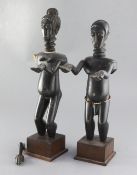 A pair of African ebonised wood figures of a man and woman standing with outstretched arms, on