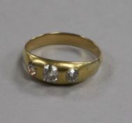 A yellow metal and three stone gypsy set diamond ring, size U/V
