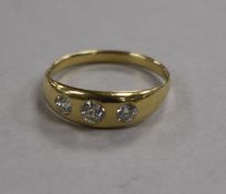 A yellow metal and gypsy set three stone diamond ring, size M.