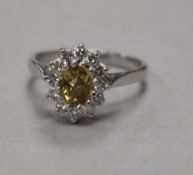 An early 1970's 18ct white gold , yellow topaz and diamond oval cluster ring, size M.
