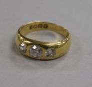 A late Victorian 18ct gold and three stone gypsy set diamond ring, size T.