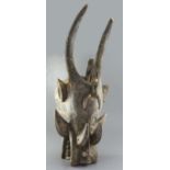 A Dogon carved wood mask with horns, tusks and teeth, height 81cm