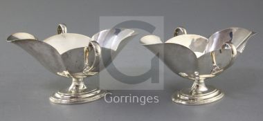 A pair of Edwardian Scottish silver double lipped two handled sauceboats by Hamilton & Inches, on