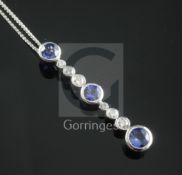 A modern white gold, sapphire and diamond drop bar pendant, set with three collet set round cut
