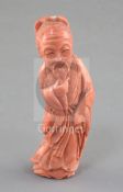 A Chinese coral figure of a sage, mid 20th century, the figure standing and stroking his beard,