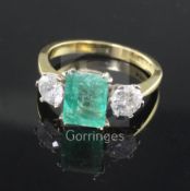 A modern 18ct gold, emerald and diamond three stone ring, the central emerald cut stone flanked by