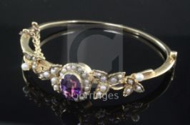 A Victorian style gold, amethyst and seed pearl cluster hinged bangle, with foliate shoulders.