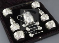 A cased Victorian repousse silver seven piece condiment set by James Deakin & Sons Ltd, with five