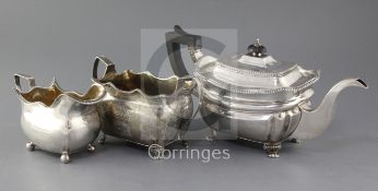 A matched George III Irish silver three piece tea set, with beaded wavy borders, engraved decoration