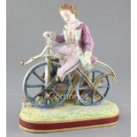 Early cycling interest: A French painted biscuit porcelain figure of a young man riding a bone