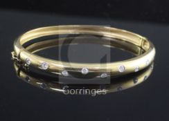 A modern 18ct gold and gypsy set diamond hinged bangle, set with eleven round cut stones.