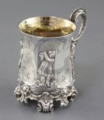 A cased Victorian ornate silver christening mug, decorated with children at various pursuits, on