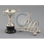 A 1940's golf interest silver toastrack surmounted by a golfer on golf ball feet by W.T. Wiseman,