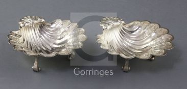 A pair of George V silver scallop dishes, Harry Freeman, with engraved decoration, on three scroll