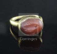 A small yellow metal ring, possibly Roman, set cabochon carnelian carved with a fish, tests as