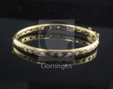 A modern gold and diamond hinged bangle, with twenty six gypsy set stones.