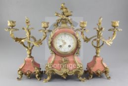 An early 20th century French pink marble clock garniture, with applied shell, scroll and dolphin