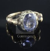 A Georgian yellow metal ring set oval sapphire in scrolled mount between seated lion shoulders,