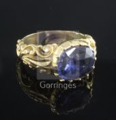 An antique yellow metal ring set with an oval sapphire in scroll-carved and pierced mount, tests