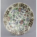 An Iznik pottery dish, Turkey c.1680 - 1720, painted with flowers and foliage within a scroll work